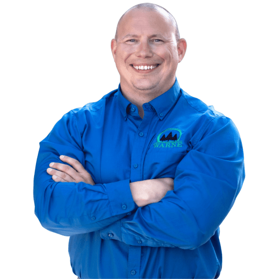 Warne Green Force Employee wearing a blue Warne shirt, smiling, and crossing his arms